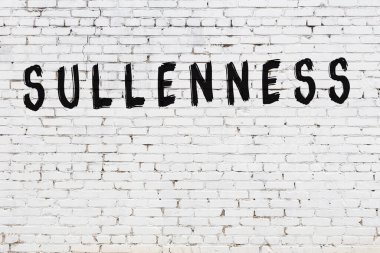 Beyaz tuğlalı duvar, siyah boyayla yazılmış somurtkan yazı.