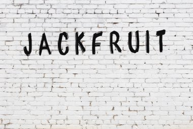 Beyaz tuğla duvarda siyah boyayla yazılmış bir meyve..