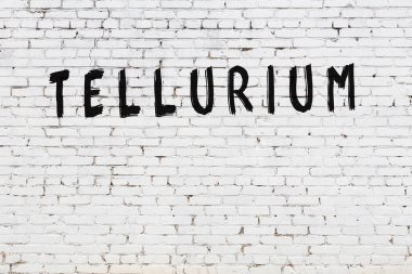 Beyaz tuğla duvara siyah boya ile yazılmış tellüdyum yazımı.