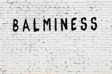 Beyaz tuğlalı duvar, siyah boyayla yazılmış.