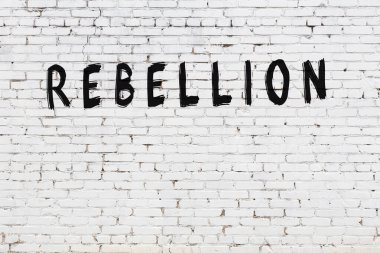 Beyaz tuğlalı duvar, siyah boyayla yazılmış bir isyan yazısı.