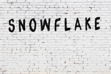 Üzerinde siyah boya ile el yazısıyla kar taneleri yazan beyaz tuğla bir duvar.