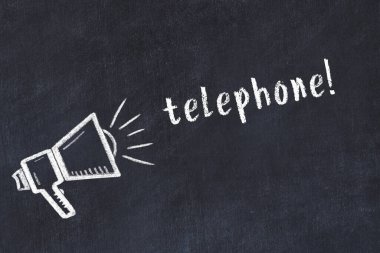 Hoparlörün tebeşir çizimi ve siyah masanın üzerine el yazısıyla yazılmış telefon.