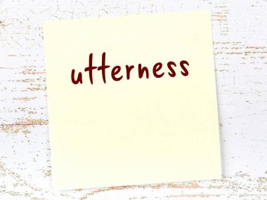 Tahta duvarda el yazısıyla yazılmış sarı yapışkan bir not var.