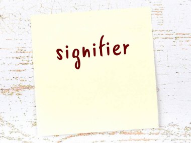 Tahta duvardaki sarı yapışkan notta el yazısıyla yazılmış bir işaret var.