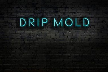 Üzerinde yazı damlası olan neon levhası tuğla duvara yapışmış. Gece görünümü
