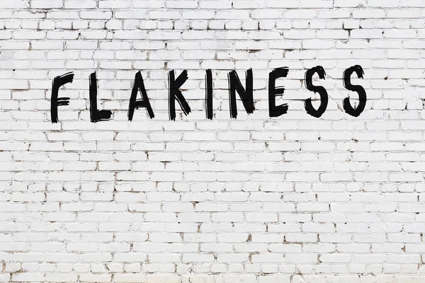 Beyaz tuğlalı duvar. Üzerinde yazı var. El yazısı siyah boya.