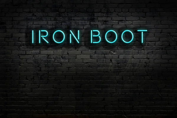 Duvara kazınmış demir çizmeli neon tabela. Gece görünümü