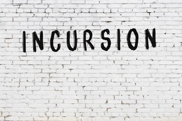 Yazıt baskını beyaz tuğla duvara siyah boya ile yazılmış..