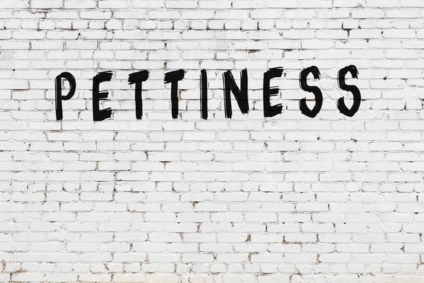 Beyaz tuğlalı duvar. Üzerinde yazı var. El yazısı siyah boya.