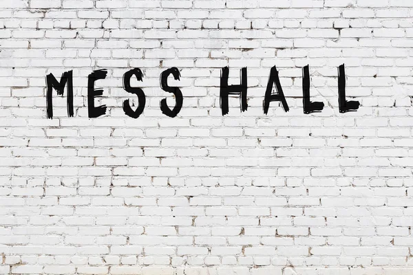 Üzerinde siyah boya olan beyaz tuğla duvarlı yemekhane.