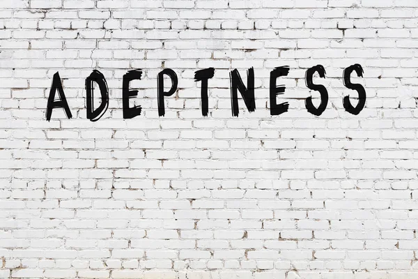 Beyaz tuğlalı duvar. Üzerinde yazı var. Elle yazılmış siyah boya.