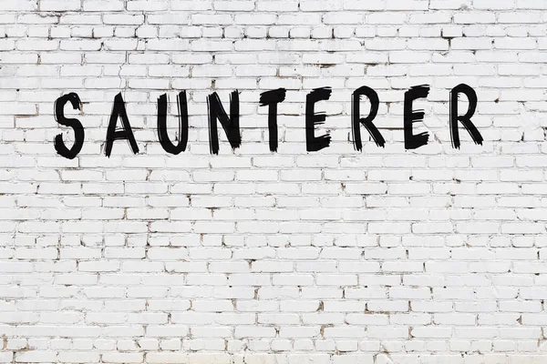 Beyaz tuğlalı duvar, siyah boyalı el yazısıyla yazması sauner.