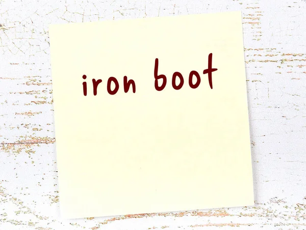 Demir çizmeyi hatırlatma kavramı. Tahta duvarda üzerinde yazı olan sarı yapışkan kağıt.