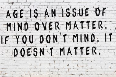 Beyaz tuğla duvara zekice alıntılar yazılı siyah bir yazı.