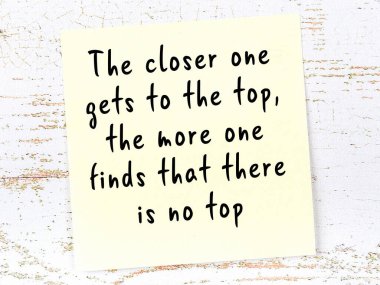 Sarı yapışkan not, ahşap duvarda el yazısıyla yazılmış zekice bir alıntıyla.