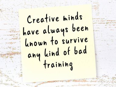 Tahta duvarda asılı sarı yapışkan nota elle yazılmış bilgece bir alıntı.