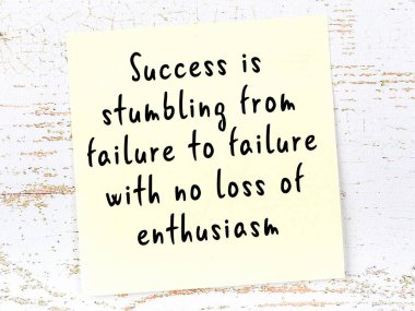 Tahta duvarda asılı sarı yapışkan nota elle yazılmış bilgece bir alıntı.