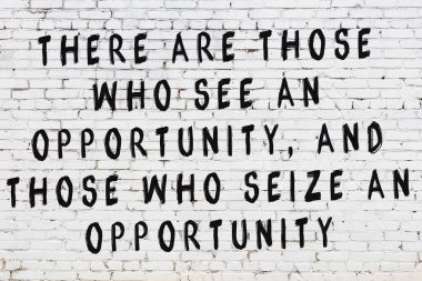 Beyaz tuğla duvara zekice alıntılar yazılı siyah bir yazı.