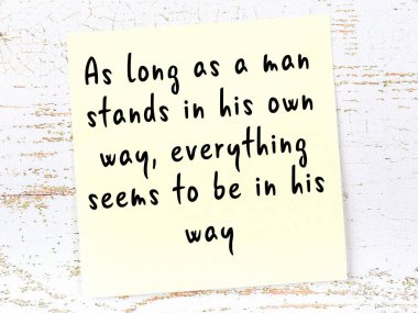 Tahta duvarda el yazısı motivasyon alıntısı olan sarı yapışkan not