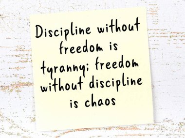 Tahta duvarda asılı sarı yapışkan nota elle yazılmış bilgece bir alıntı.