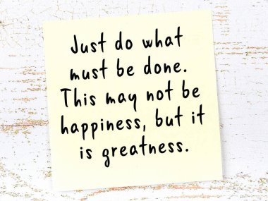 Sarı yapışkan not, ahşap duvarda el yazısıyla yazılmış zekice bir alıntıyla.