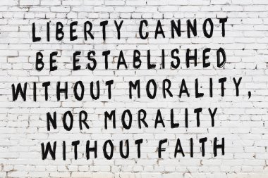 Beyaz tuğla duvara zekice alıntılar yazılı siyah bir yazı.