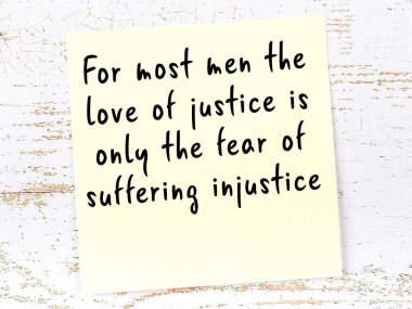 Tahta duvarda el yazısı motivasyon alıntısı olan sarı yapışkan not