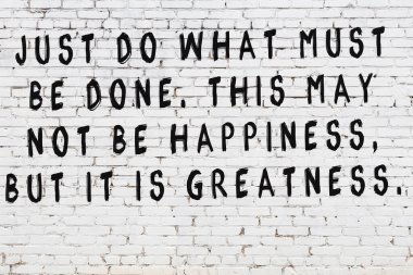 Beyaz tuğla duvara zekice alıntılar yazılı siyah bir yazı.