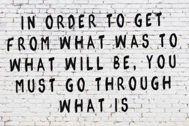 Beyaz tuğla duvar ve bilgece alıntıların yazılı olduğu siyah yazı.