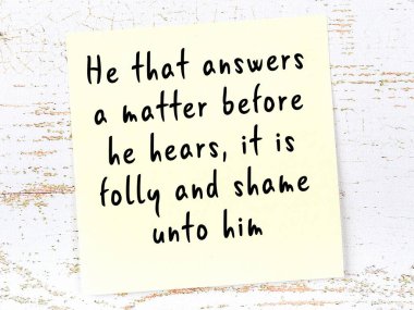 Tahta duvarda asılı sarı yapışkan nota elle yazılmış bilgece bir alıntı.