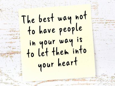 Tahta duvarda asılı sarı yapışkan nota elle yazılmış bilgece bir alıntı.