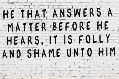 Beyaz tuğla duvar ve bilgece alıntıların yazılı olduğu siyah yazı.