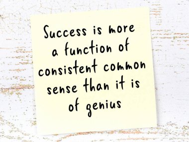 Tahta duvarda asılı sarı yapışkan nota elle yazılmış bilgece bir alıntı.