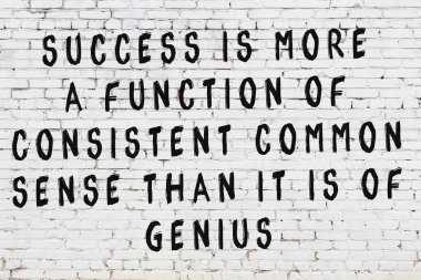 Beyaz tuğla duvara zekice alıntılar yazılı siyah bir yazı.