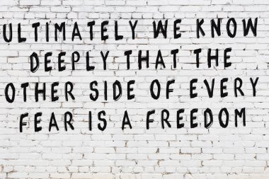 Beyaz tuğla duvar ve bilgece alıntıların yazılı olduğu siyah yazı.