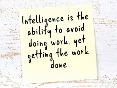 Sarı yapışkan not, ahşap duvarda el yazısıyla yazılmış zekice bir alıntıyla.