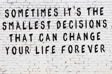 Beyaz tuğla duvar ve bilgece alıntıların yazılı olduğu siyah yazı.