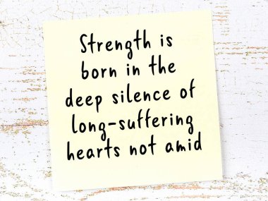 Tahta duvarda asılı sarı yapışkan nota elle yazılmış bilgece bir alıntı.