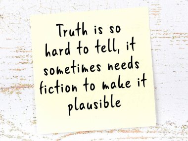 Tahta duvarda asılı sarı yapışkan nota elle yazılmış bilgece bir alıntı.