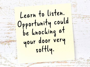 Sarı yapışkan not, ahşap duvarda el yazısıyla yazılmış zekice bir alıntıyla.