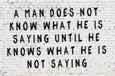 Beyaz tuğla duvar ve bilgece alıntıların yazılı olduğu siyah yazı.