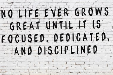 Beyaz tuğla duvara zekice alıntılar yazılı siyah bir yazı.