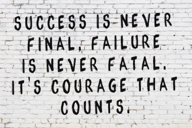 Beyaz tuğla duvara zekice alıntılar yazılı siyah bir yazı.