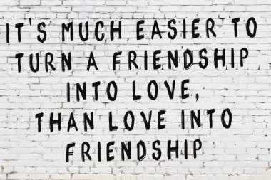 Beyaz tuğla duvara zekice alıntılar yazılı siyah bir yazı.