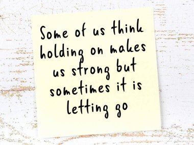 Tahta duvarda el yazısı motivasyon alıntısı olan sarı yapışkan not