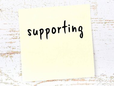 Destekleme konusunda hatırlatma kavramı. Tahta duvarda üzerinde yazı olan sarı yapışkan kağıt.