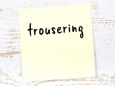 Tahta duvarda el yazısıyla yazılmış sarı yapışkan bir not var.