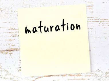 Olgunlaşma hakkında hatırlatma kavramı. Tahta duvarda üzerinde yazı olan sarı yapışkan kağıt.