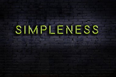 Tuğla duvara karşı basitçe yazılmış neon levhası. Gece görünümü